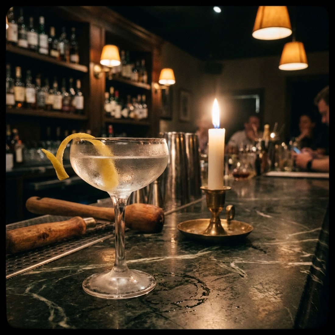 A coupe cocktail glass with gold leaf floating on the surface