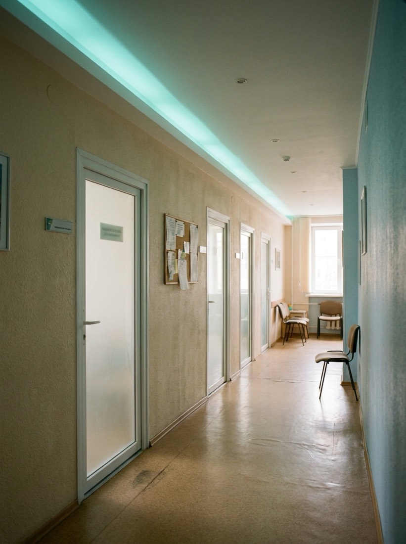 A frosted-glass corridor inside the studio leading toward the private treatment suites