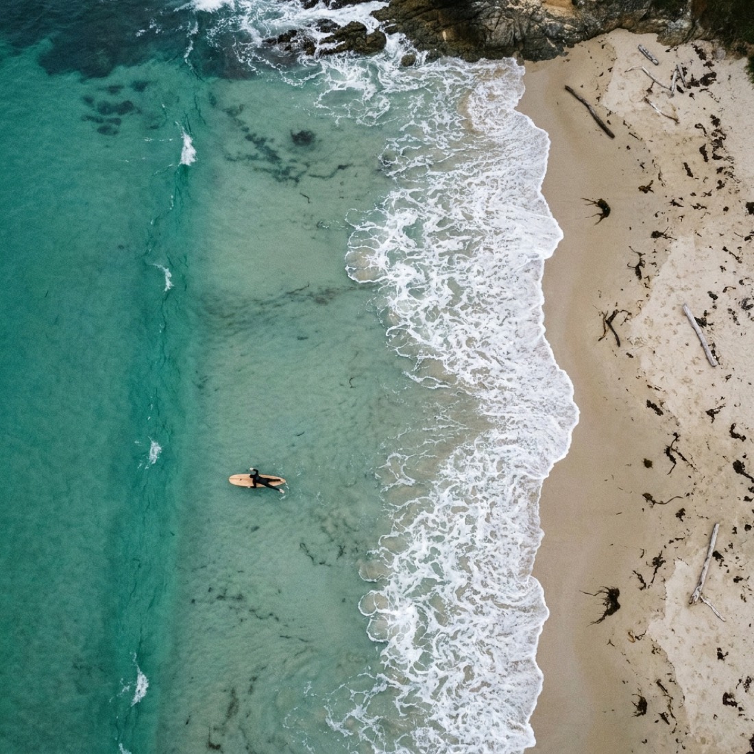 Aerial view of turquoise water meeting the sandy shoreline